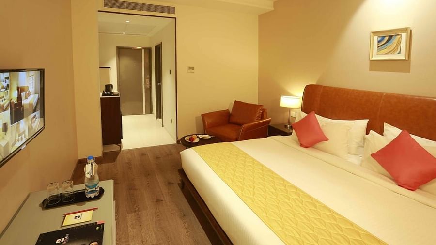 Executive Room at Mayberry Tiruppur with a view of the bed, sofa, and wall-mounted TV, with the room door visible in the background